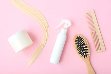 A lock of blonde hair, hair care products and a comb on a colored backgroundの写真素材