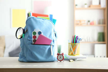 School backpack and stationery in a bright room.