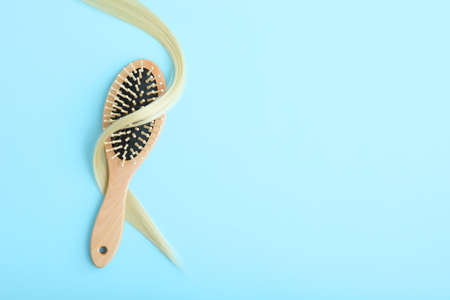 A lock of blonde hair, hair care products and a comb on a colored backgroundの写真素材