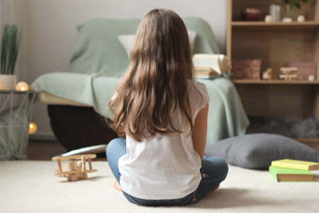 Lonely sad girl at home. saddened alarmed child alone at home.の写真素材