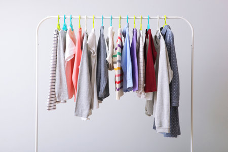 Children clothes on a rack on a light background.の写真素材