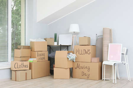 Cardboard boxes and household stuff in empty room.