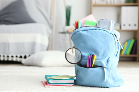 School backpack and stationery in a bright room.