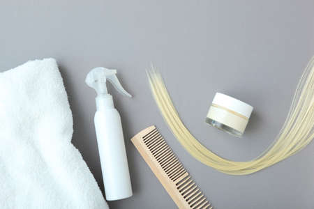 A lock of blonde hair, hair care products and a comb on a colored backgroundの写真素材