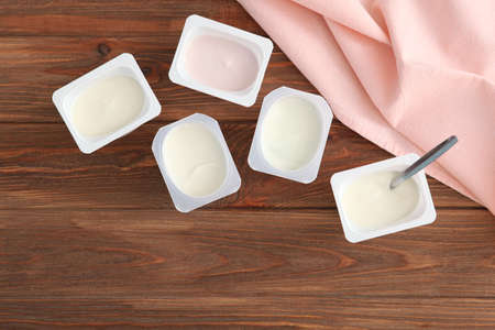 Tasty yogurt in a plastic glass on a colored table. Place to insert text.