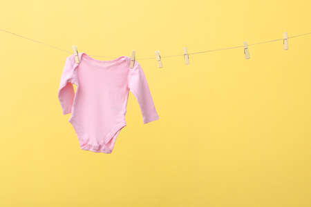 Baby clothes on a rope on a colored background.の写真素材