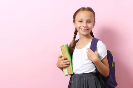 Cute smiling schoolgirl with a school backpack on a colored background.の写真素材