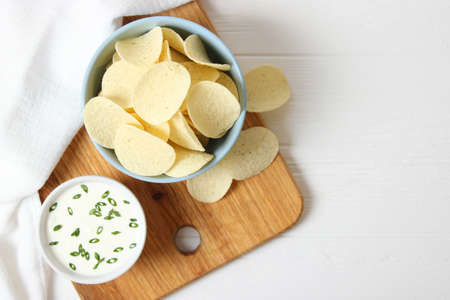 Potato chips and sauce on the table.