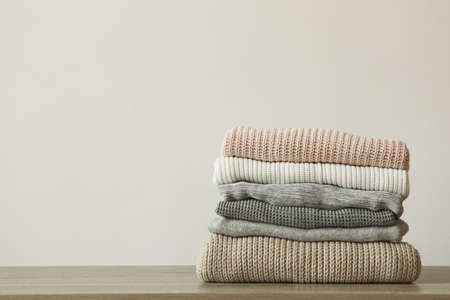 a stack of warm sweaters on the table on a colored background.