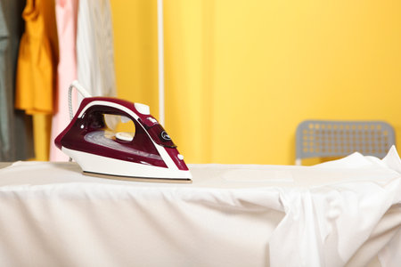 Iron and a clothes on an ironing board on a colored background.の写真素材