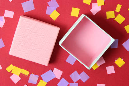 open gift box and confetti on a colored background top view.の写真素材