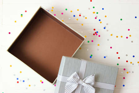 open gift box and confetti on a colored background top view.の写真素材