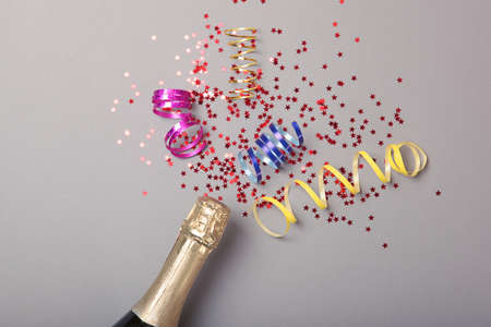 Champagne bottle, glasses and confetti on a colored background top view.の写真素材