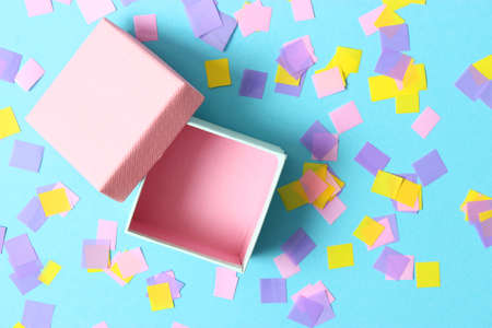 open gift box and confetti on a colored background top view.の写真素材
