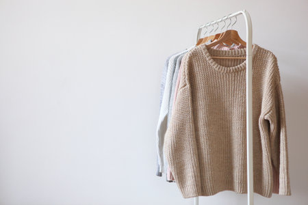 Warm sweaters on a wardrobe hanger on a colored background.