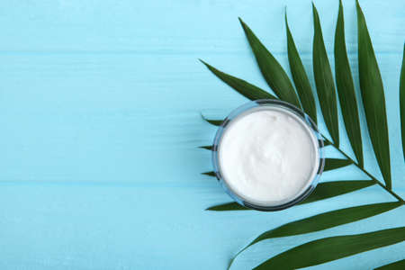 Care cream and flowers on a colored background top view. Skin care cosmetics.