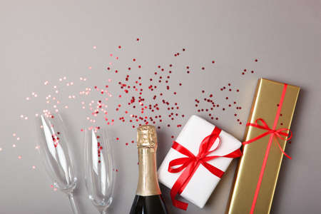 Champagne bottle, glasses and confetti on a colored background top view.の写真素材