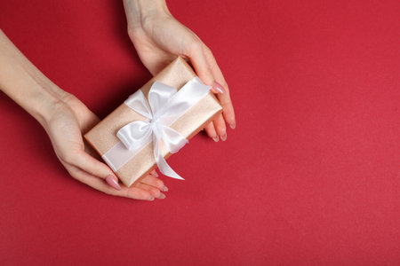 gift in female hands on a colored background top view.の写真素材