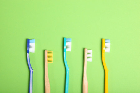 natural bamboo toothbrushes and plastic on a colored background top view.
