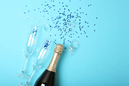Champagne bottle, glasses and confetti on a colored background top view.の写真素材