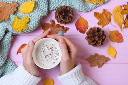 Autumn composition top view. Cup of coffee in the hands and autumn leavesの写真素材