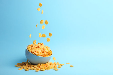 Delicious cornflakes falling into a plate on a colored background.の写真素材