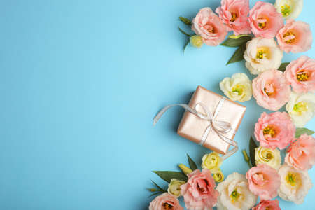 flower arrangement and gift on colored background top view with place for textの写真素材