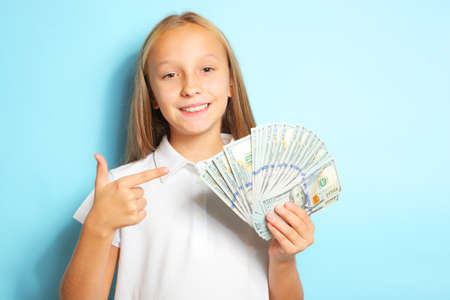 Girl holding money in hands on a blue background close upの写真素材