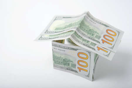 Dollar bills and a figurine of a house on a colored background. mortgageの写真素材