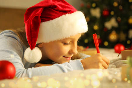 Beautiful little girl writing a letter to Santa Claus in the Christmas interiorの写真素材