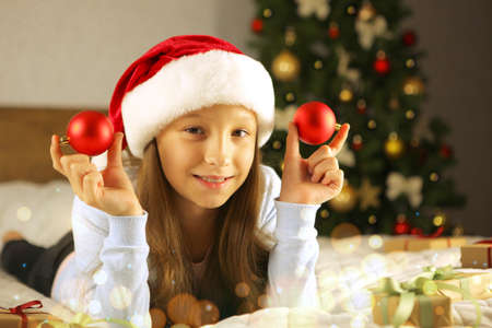beautiful little girl in a good mood with gifts in the Christmas interior.の写真素材