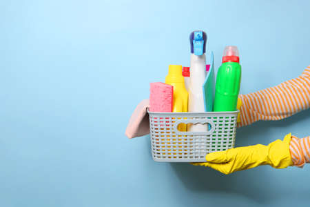A set of cleaning products in female hands on a colored backgroundの写真素材
