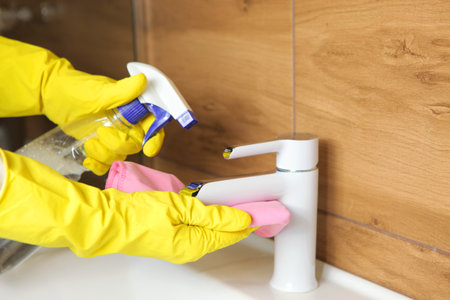 Woman cleans up the sink and faucet in the bathroom, cleaning and disinfectionの写真素材