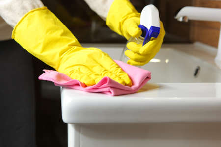 Woman cleans up the sink and faucet in the bathroom, cleaning and disinfectionの写真素材