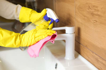 Woman cleans up the sink and faucet in the bathroom, cleaning and disinfectionの写真素材