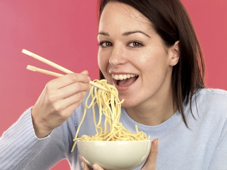 Young Woman Eating Noodlesの写真素材