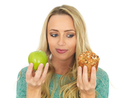 Young Woman Holding and Comparing Cake and Fruitの写真素材