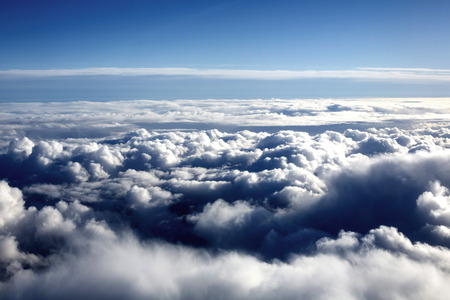 Looking Down at White Fluffy Dramatic Clouds Against a Blue Skyの写真素材
