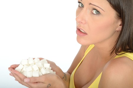 Attractive Young Woman in Her Twenties Holding a Handful of White Sugar Cubes Looking at the Cameraの写真素材