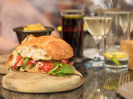 Vegetarian Red Pepper and Rocket Ciabatta Bread Sandwich or Roll with a Glass of White Wine and Waterの写真素材