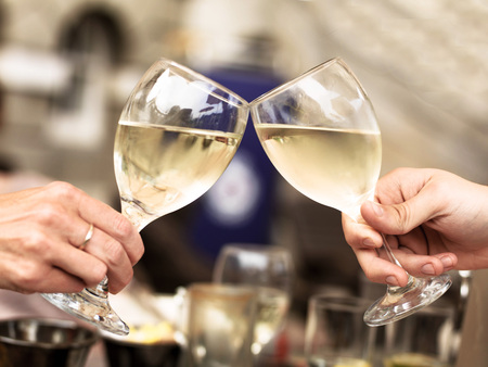 Two People Touching Glasses of White Wine Celebrating an Event or Good Newsの写真素材