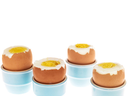 Four Boiled Eggs in Blue China Egg Cups With Their Tops Removed Ready To Eatの写真素材