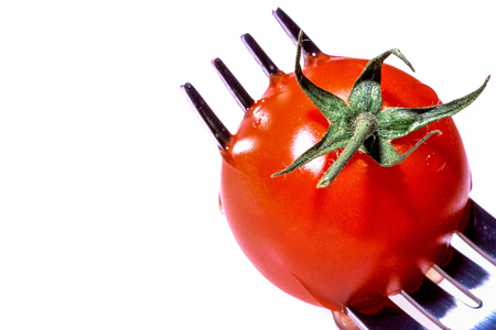 Creative Image of a Single Cherry Tomato on a Fork Against a White Background With Copy Spaceの写真素材