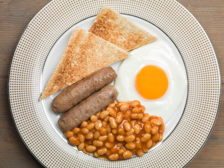 Cooked Fried English Breakfast of Pork Sausages Fried Egg and Baked Beans With Toastの写真素材