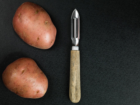 Traditional Potato Peeler With Two Uncooked Potatoesの写真素材