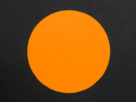 Solid Orange Disc or Circle Against a Black Background With Copy Spaceの写真素材