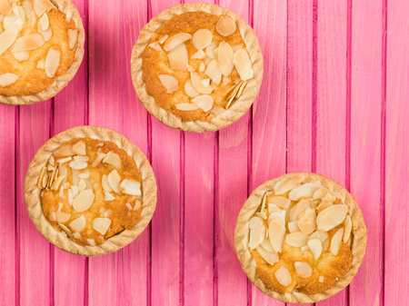 Four Bakewell Tarts With Almonds on a Wooden Pink Backgroundの写真素材