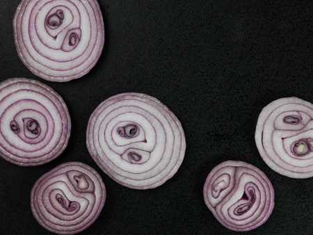 Sliced Raw Uncooked Red Onions Against a Black Backgroundの写真素材
