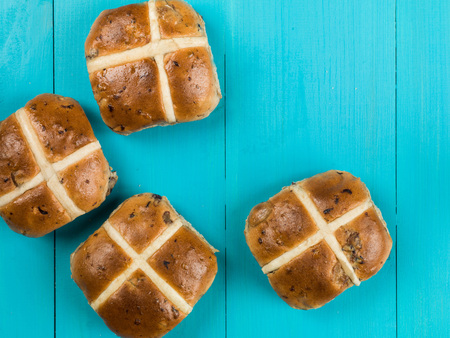 Four Hot Cross Buns Easter Food Against a Blue Backgroundの写真素材