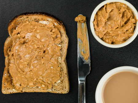Crunchy Peanut Butter Spread on Toast Against a Black Backgroundの写真素材